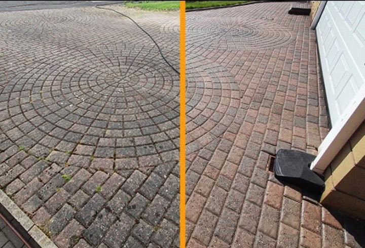 A block-paved driveway beside a garage, with the cleaned half looking brighter